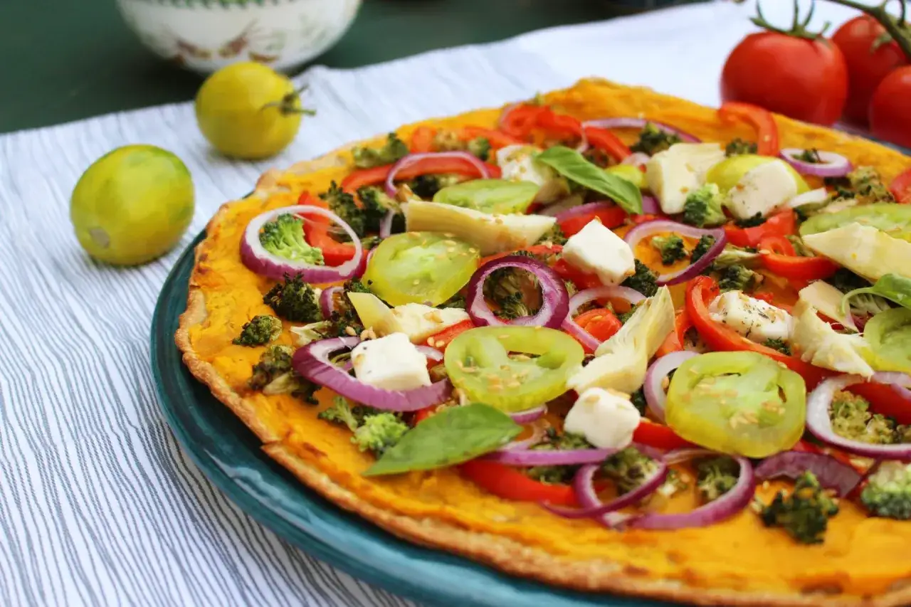 Pizza colorée aux légumes, parfaite pour une recette d'été. Brocolis, tomates, oignons rouges et mozzarella sur une pâte dorée.
