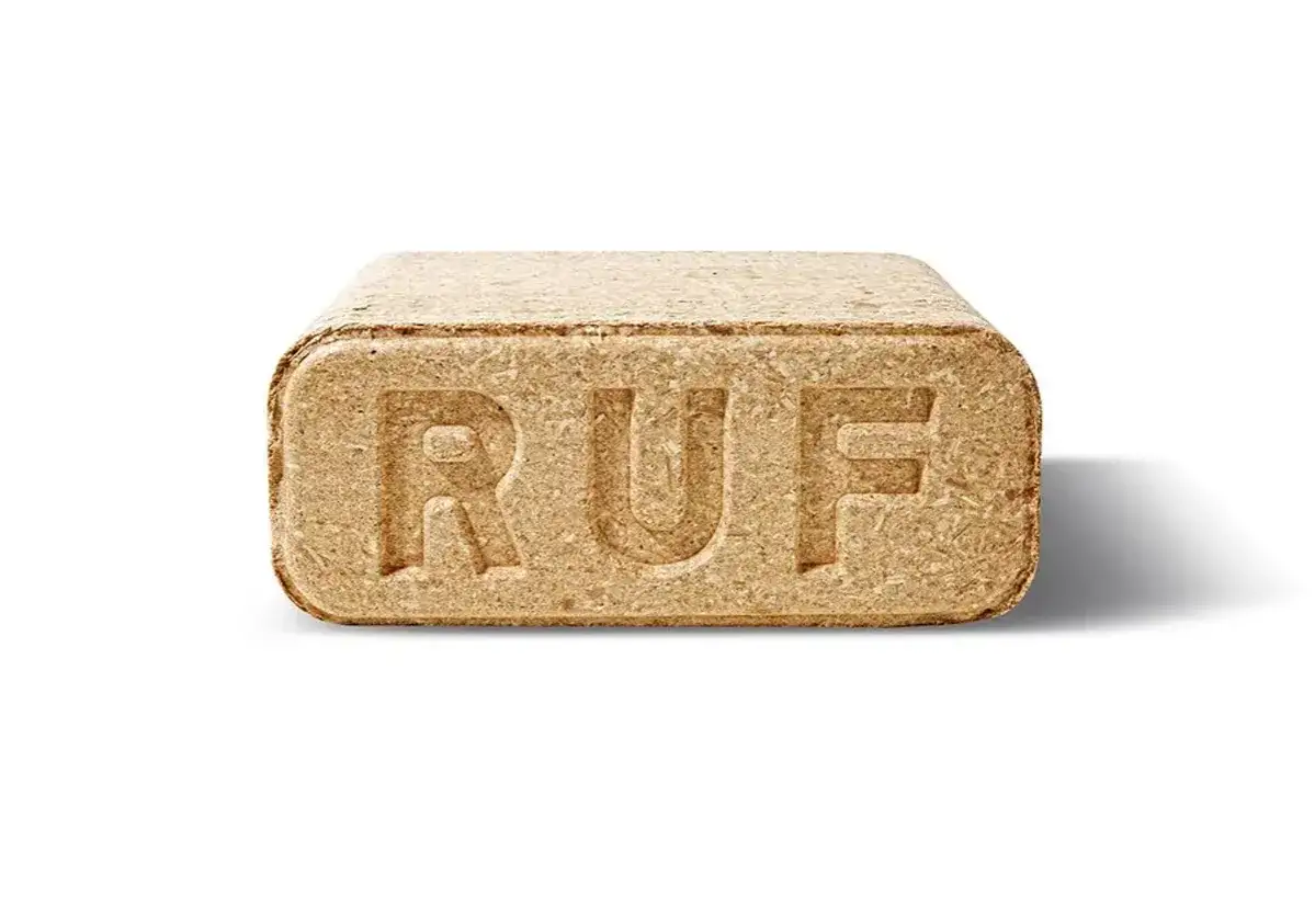 Brykiet drzewny RUF, prasowany z trocin, z wytłoczonym logo. Wygląda jak mała, zbita cegiełka z drewna.