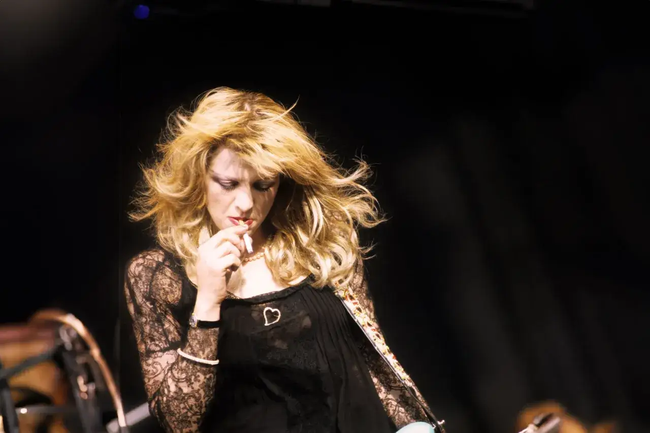 Courtney Love, wokalistka zespołu, z papierosem w dłoni, w czarnej koronkowej bluzce.