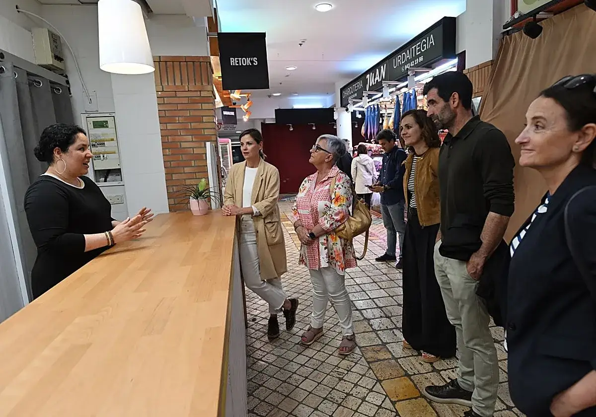 Un grupo de personas escucha atentamente mientras una mujer explica cómo crear una comunidad en un mercado local.