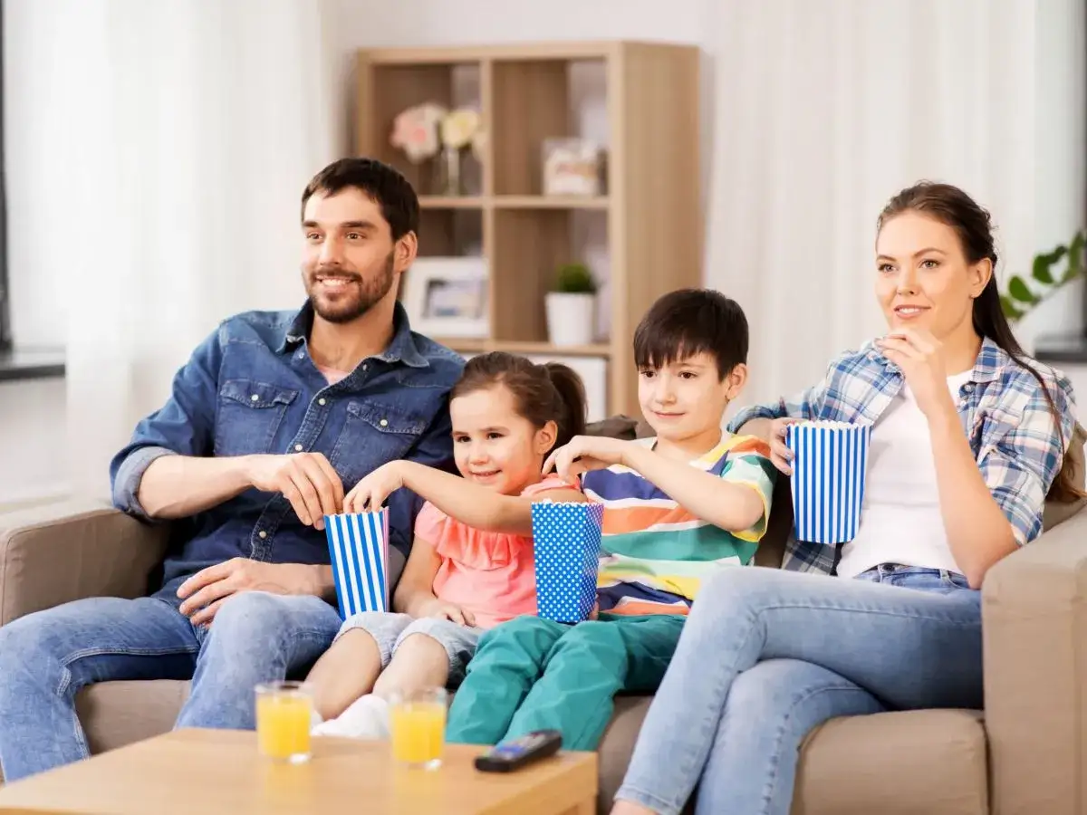 Familia disfrutando de palomitas mientras ven películas protagonizadas por niños.