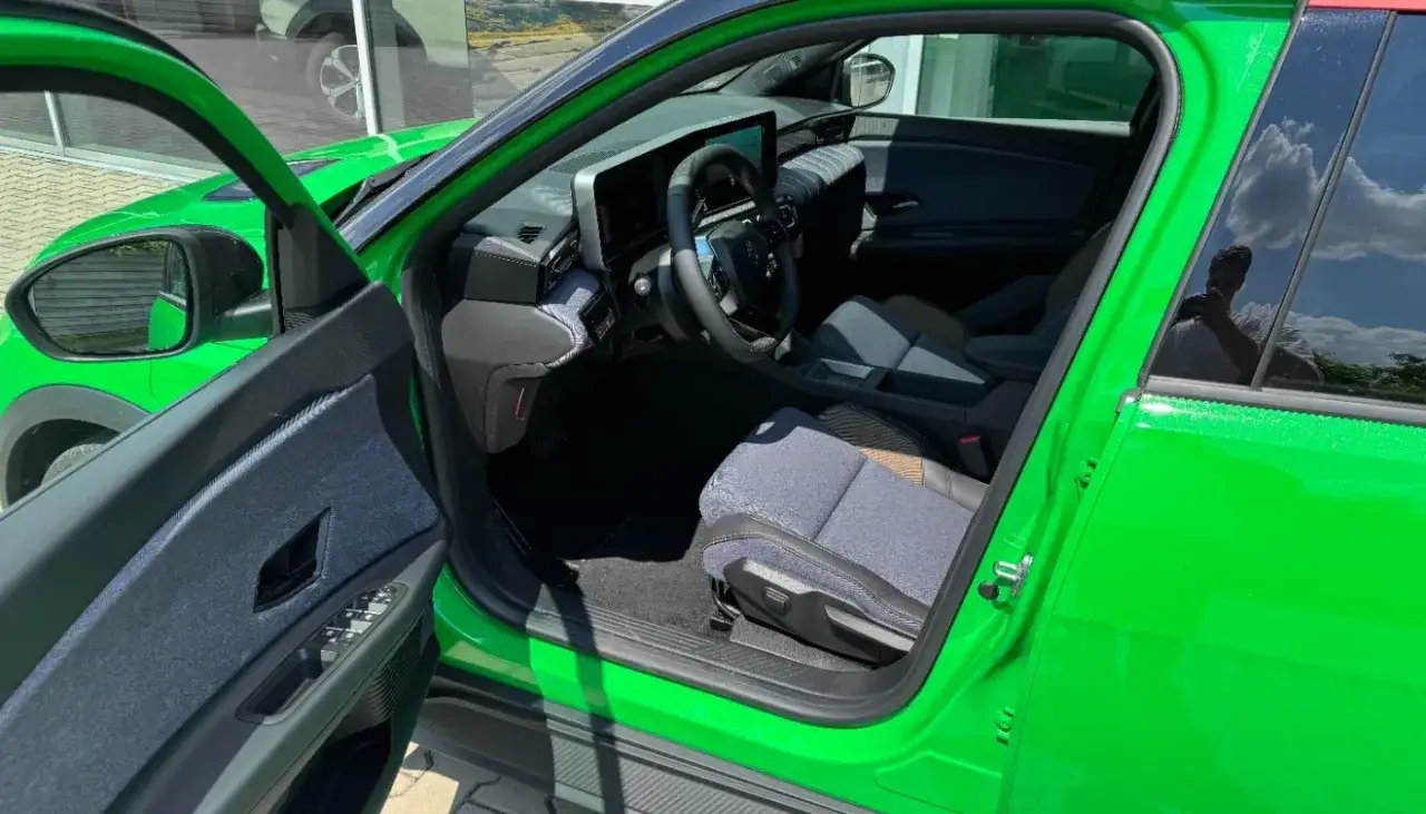 Wnętrze jaskrawozielonego Renault 5 electric z niebieskimi akcentami i nowoczesnym kokpitem.
