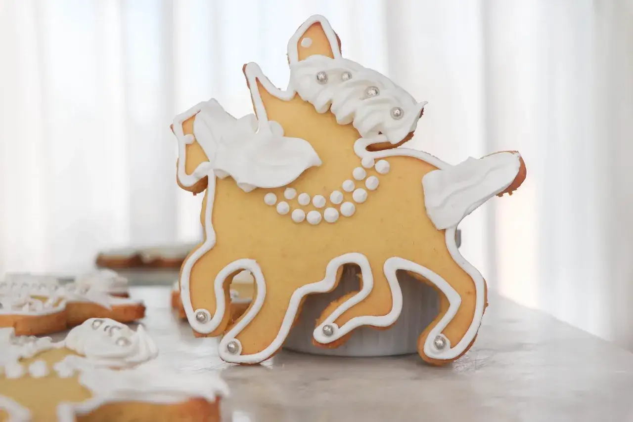 Biscotto a forma di cavallo decorato con glassa bianca e perline argentate, un dolce San Martino che racconta una storia di festa.