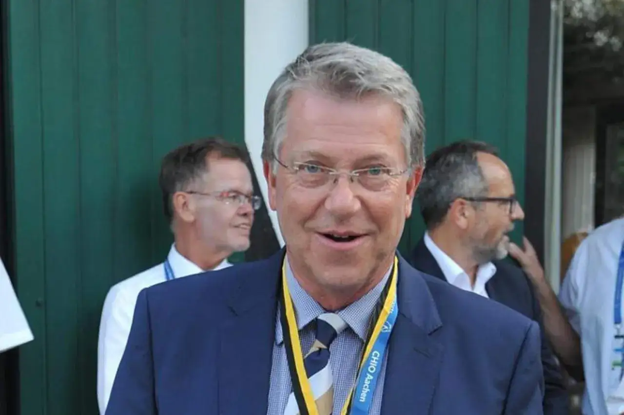 Carsten Sostmeier l&auml;chelt in die Kamera, tr&auml;gt einen blauen Anzug und ein Namensschild vom CHIO Aachen.
