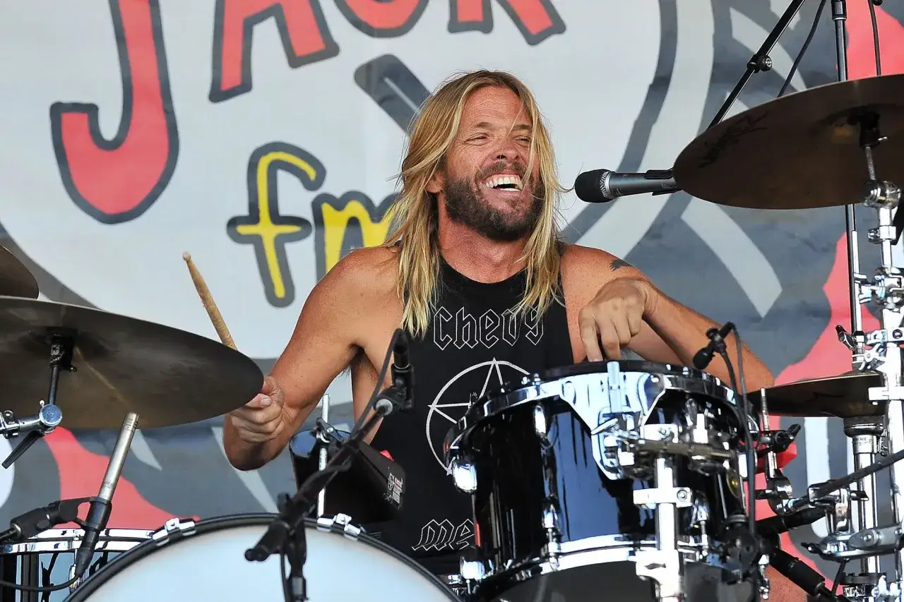 Perkusista Foo Fighters, Taylor Hawkins, z uśmiechem na twarzy gra na perkusji podczas koncertu.