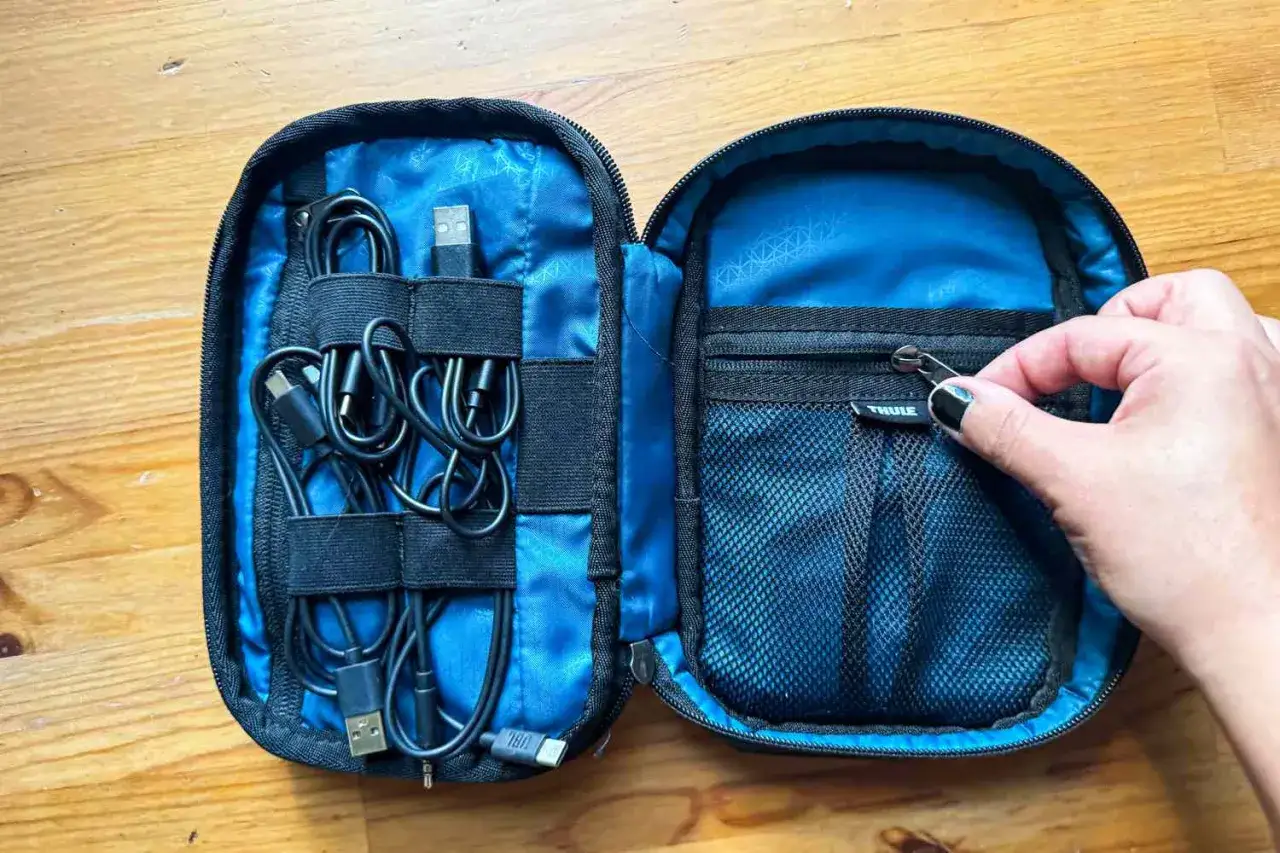 Torba podr&oacute;żna z przegr&oacute;dkami na kable i zapinkami do ich porządkowania. W środku czarne kable USB i słuchawki.