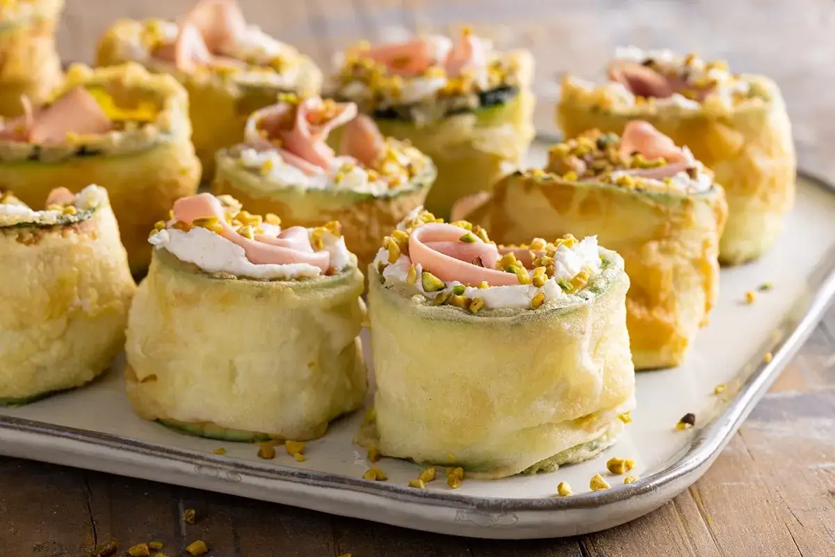 Deliziosi involtini di zucchine fritti, ripieni di crema, prosciutto e pistacchi sbriciolati.