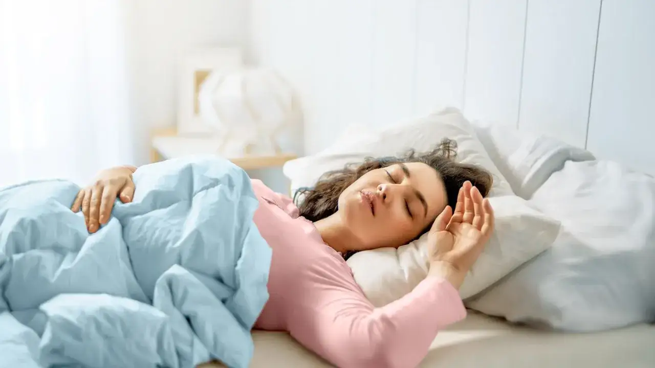 Mujer durmiendo pl&aacute;cidamente, quiz&aacute;s experimentando alucinaciones hipnag&oacute;gicas, envuelta en una manta azul y vestida de rosa.