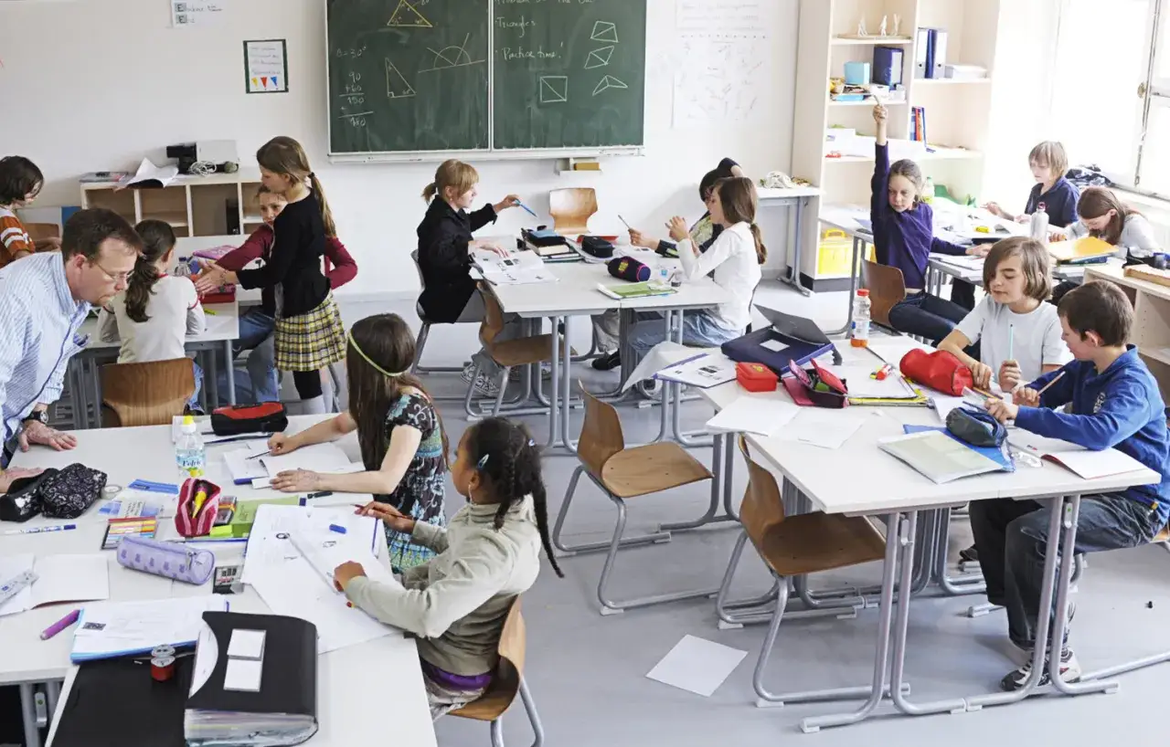 Schüler arbeiten in einer hellen Finnland Schule. Ein Lehrer hilft den Kindern bei ihren Aufgaben.