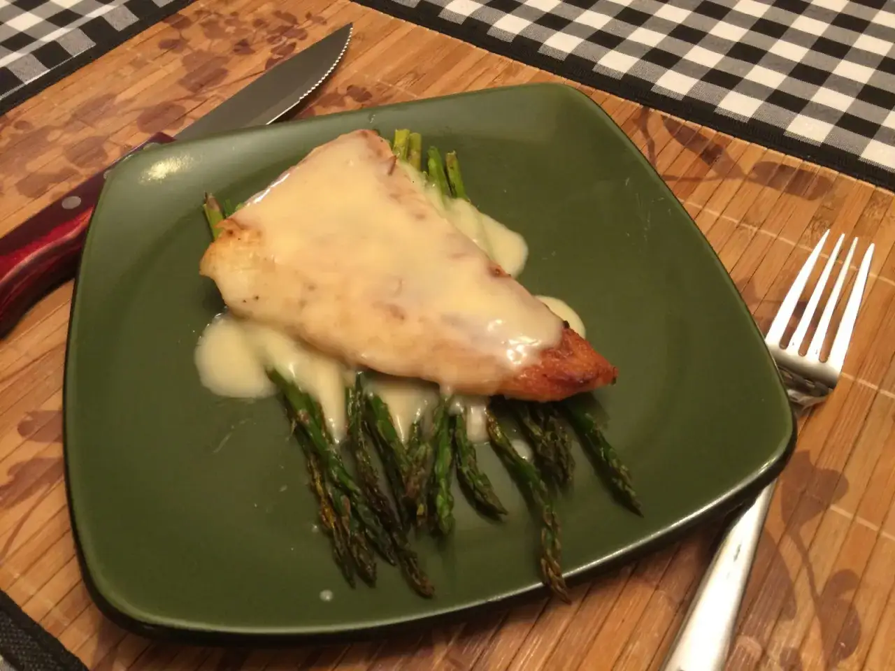 Fiskfil&eacute; med sparris och kr&auml;mig beurre blanc-s&aring;s p&aring; en gr&ouml;n tallrik. En kniv och gaffel ligger bredvid.