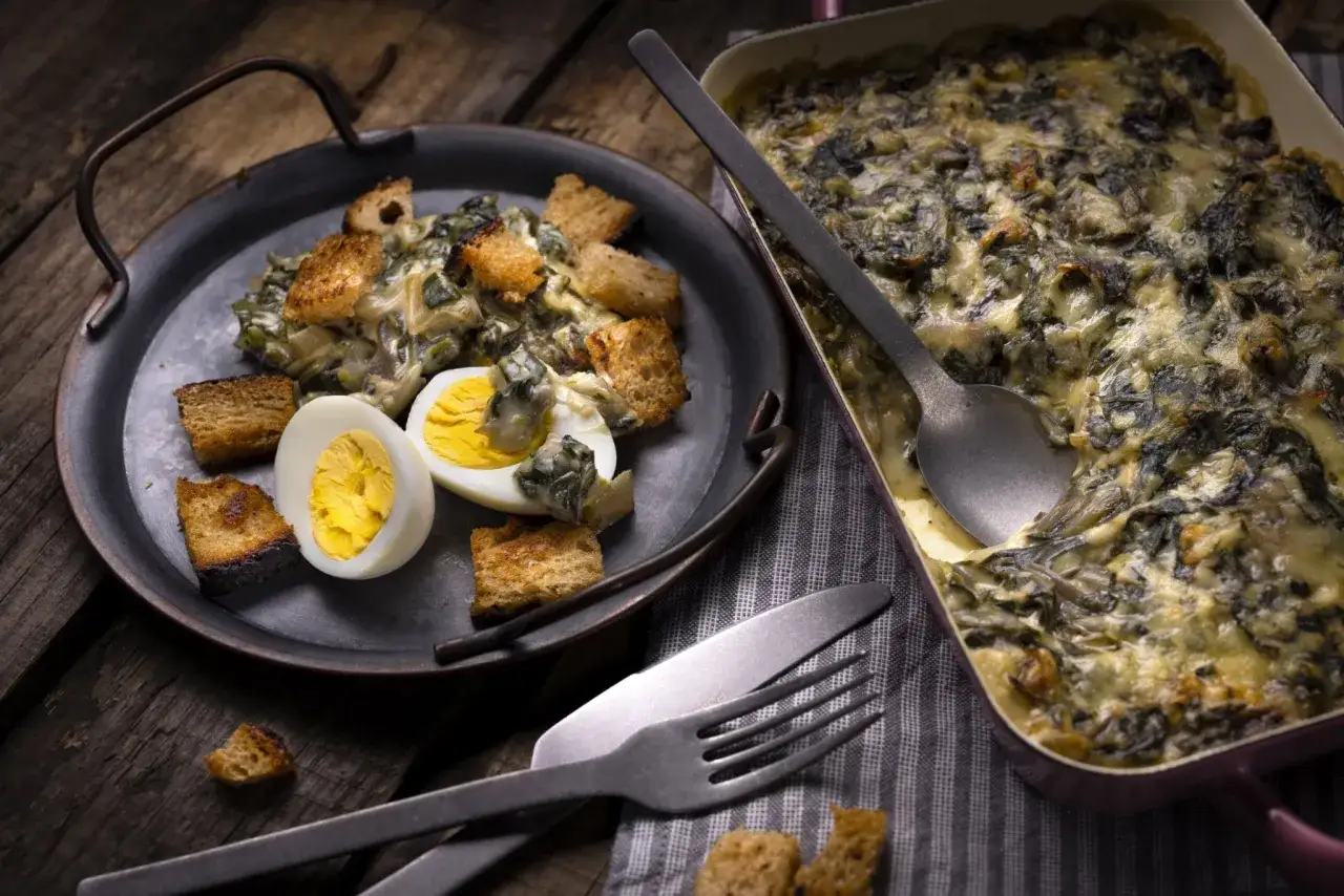 Un plat de gratin de blettes, garni de cro&ucirc;tons et d'un &oelig;uf dur, pr&ecirc;t &agrave; &ecirc;tre d&eacute;gust&eacute;.