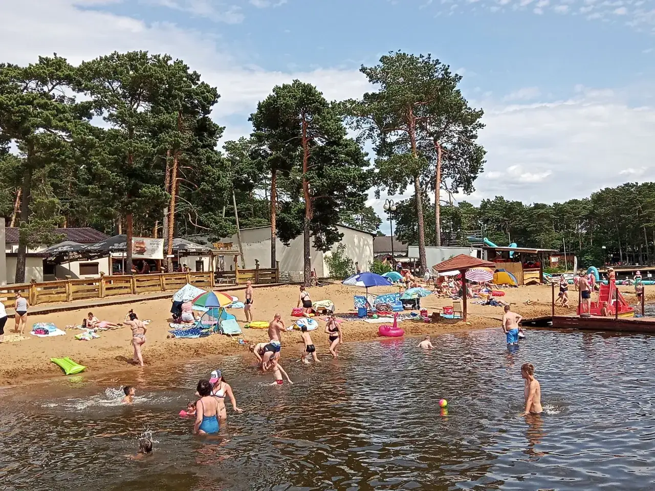 Sielpia jezioro tętni życiem. Ludzie kąpią się, opalają i bawią na piaszczystej plaży, ciesząc się letnim dniem.