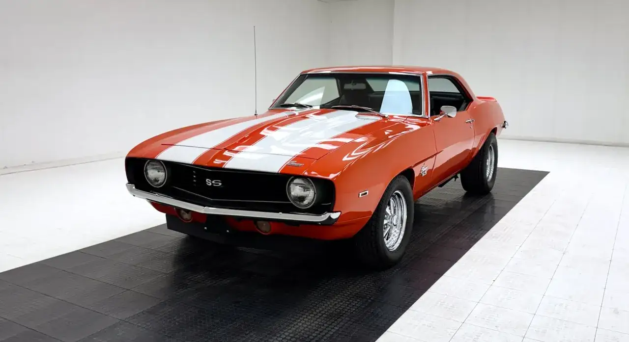 En orange Chevrolet Camaro SS 1969 med vita ränder, en ikonisk muskelbil redo för vägen.