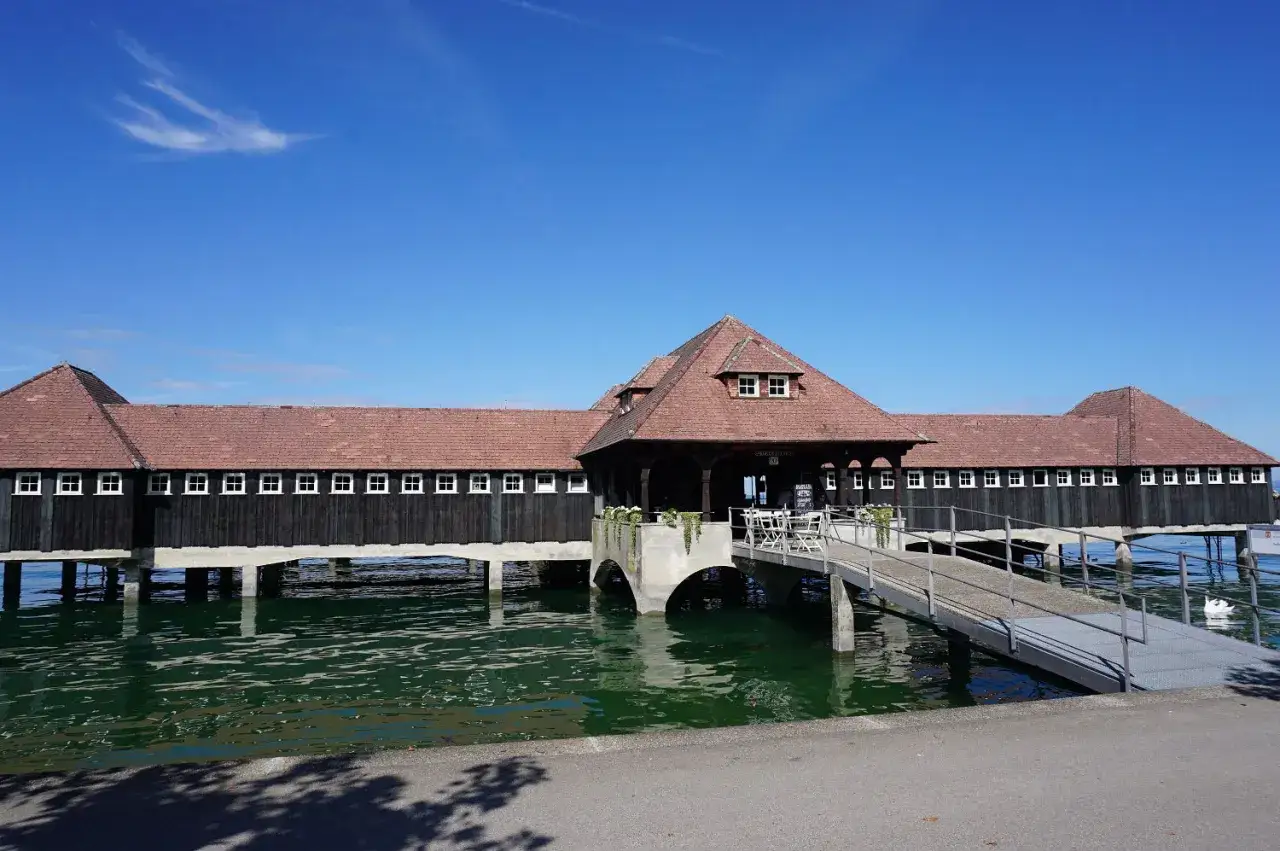 Holzbrücke über dem St. Galler See mit roten Ziegeldächern und vielen Fenstern. Ein Steg führt zu einem Café.