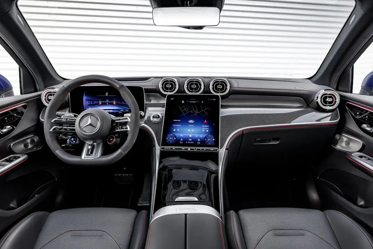 Wnętrze nowoczesnego **Mercedes GLC SUV** z cyfrowymi zegarami, dużym ekranem dotykowym i sportową kierownicą.