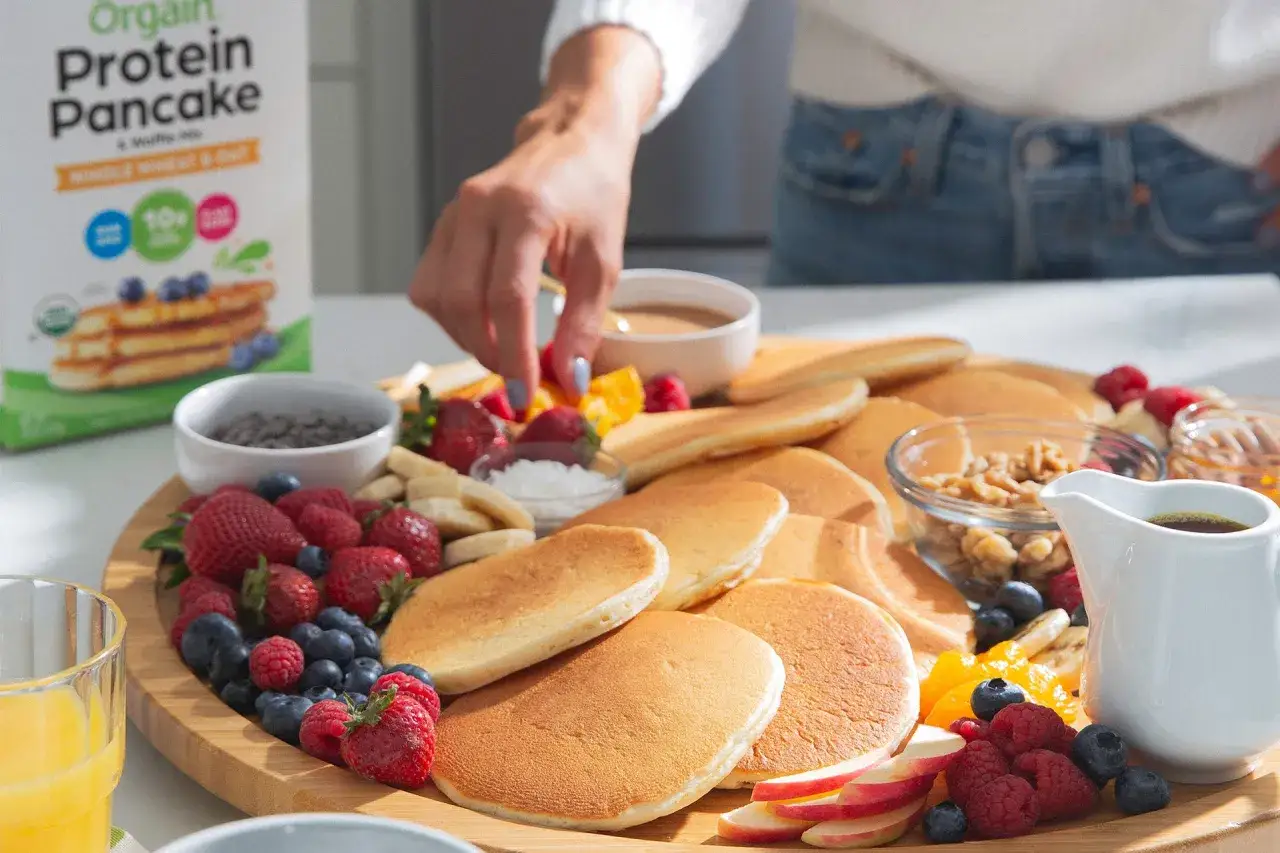 Ein bunter Teller mit Protein-Pfannkuchen, Beeren, Nüssen und Obst – perfekt für den proteinreichen Snack nach dem Training.