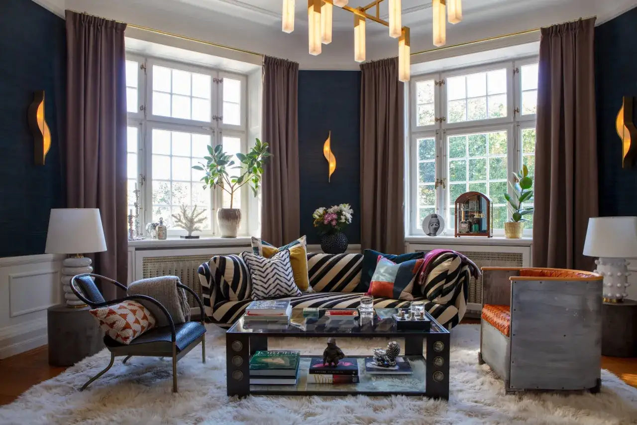 Ett lyxigt vardagsrum med en randig soffa, en unik f&aring;t&ouml;lj och en glaskoppsbord. Sofia Wallenstam har skapat en elegant och personlig atmosf&auml;r.