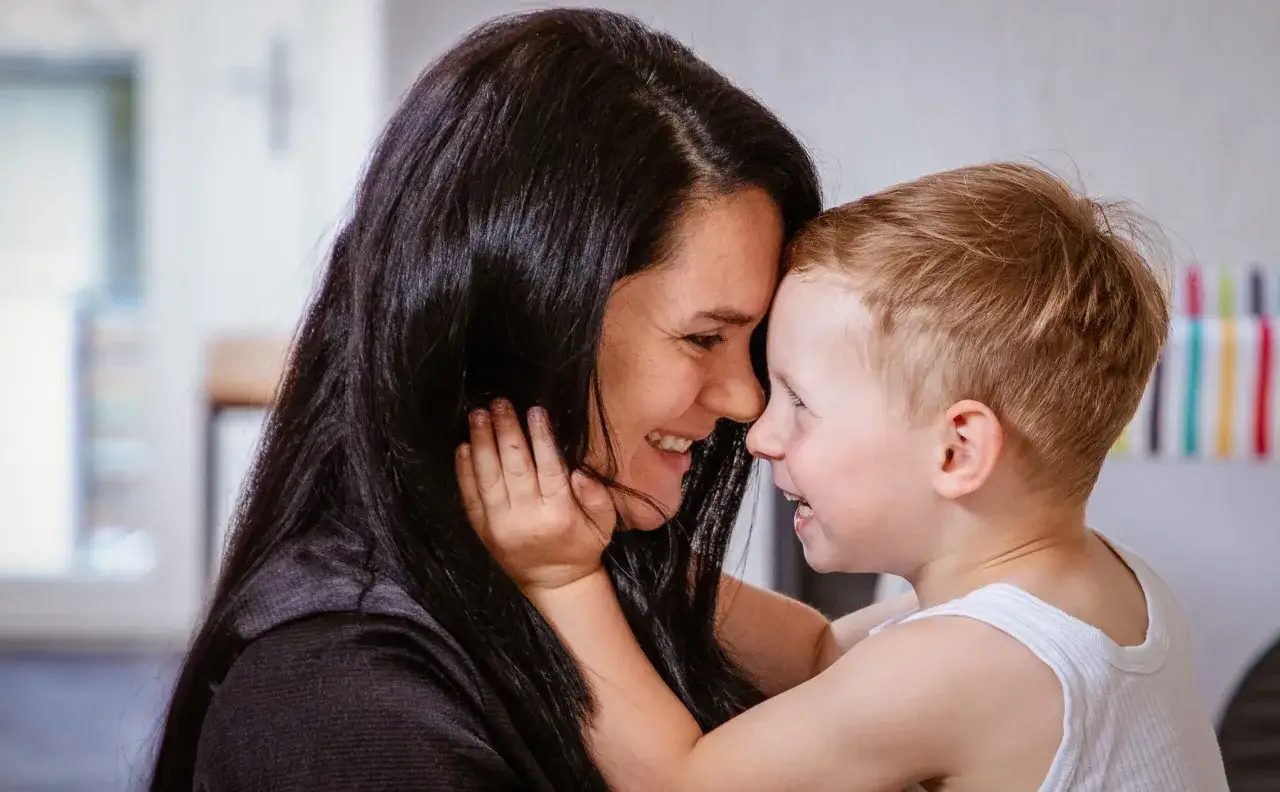 Madre e hijo comparten un momento tierno, fomentando el aprendizaje social y emocional a través de la conexión.