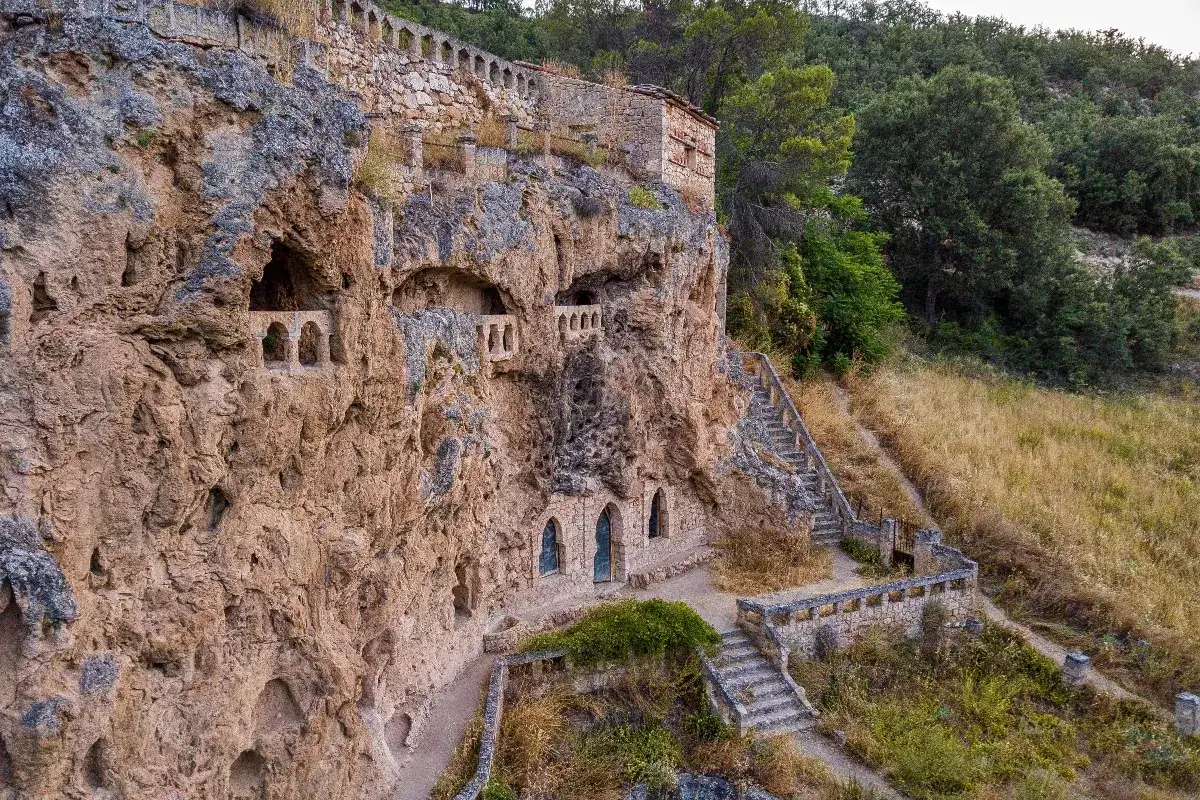 Antiguas cuevas civicas excavadas en la roca, con arcos y escaleras que suben hacia la vegetaci&oacute;n. Una cascada de historia y piedra.