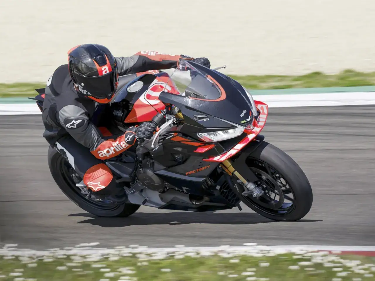 Piloto en una Aprilia RS 660 full black, inclin&aacute;ndose en una curva en circuito.