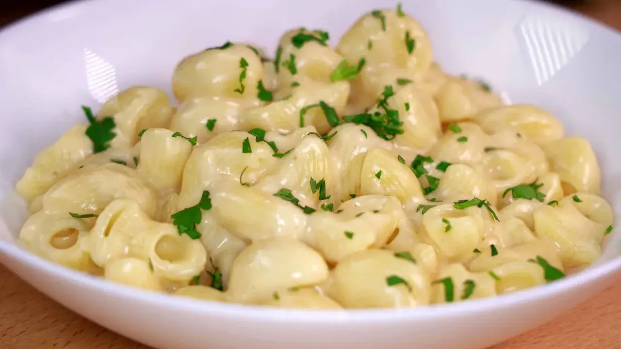 Un plato cremoso de macarrones con queso, cubierto con perejil fresco picado.