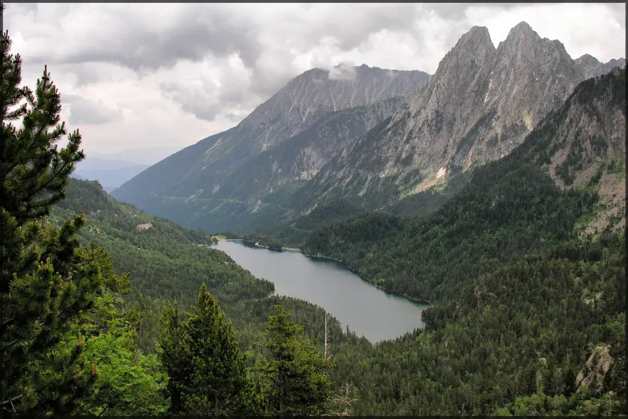 Paisaje montañoso con un lago y bosques frondosos. Ideal para explorar rutas desde Espot.
