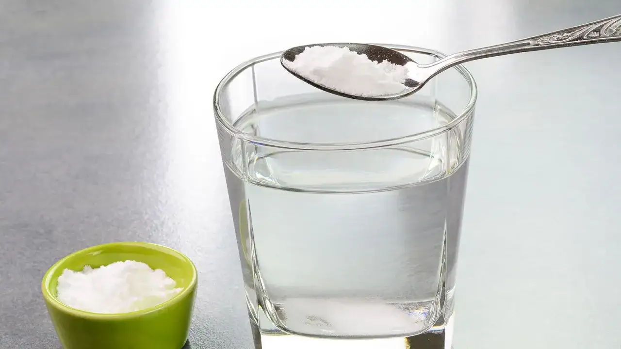 Cuchara con bicarbonato lista para añadir a un vaso de agua. Descubre los agua con bicarbonato beneficios para tu salud.
