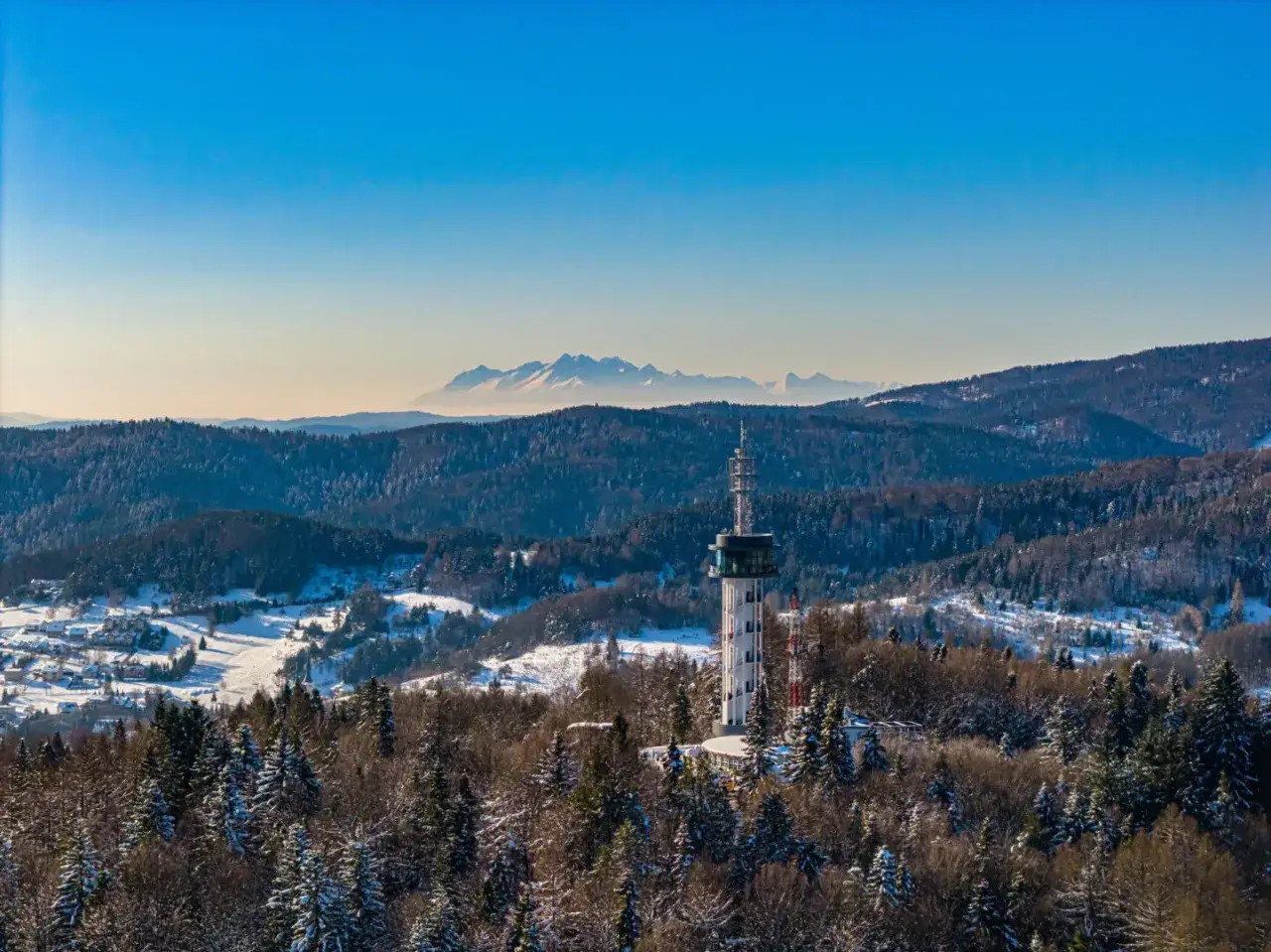 Skiełek wieża widokowa góruje nad ośnieżonym krajobrazem. W oddali majaczą Tatry.