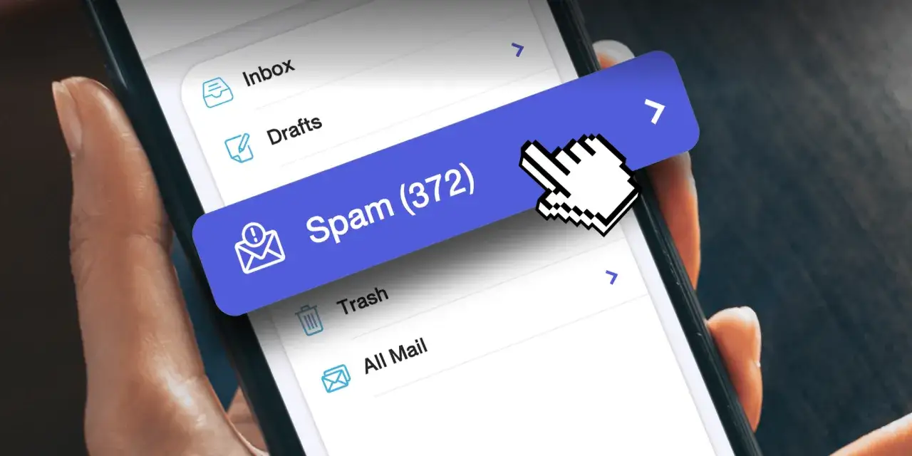 Dłoń trzyma smartfon, na ekranie którego widać listę folderów poczty e-mail. Jeden z nich, oznaczony jako