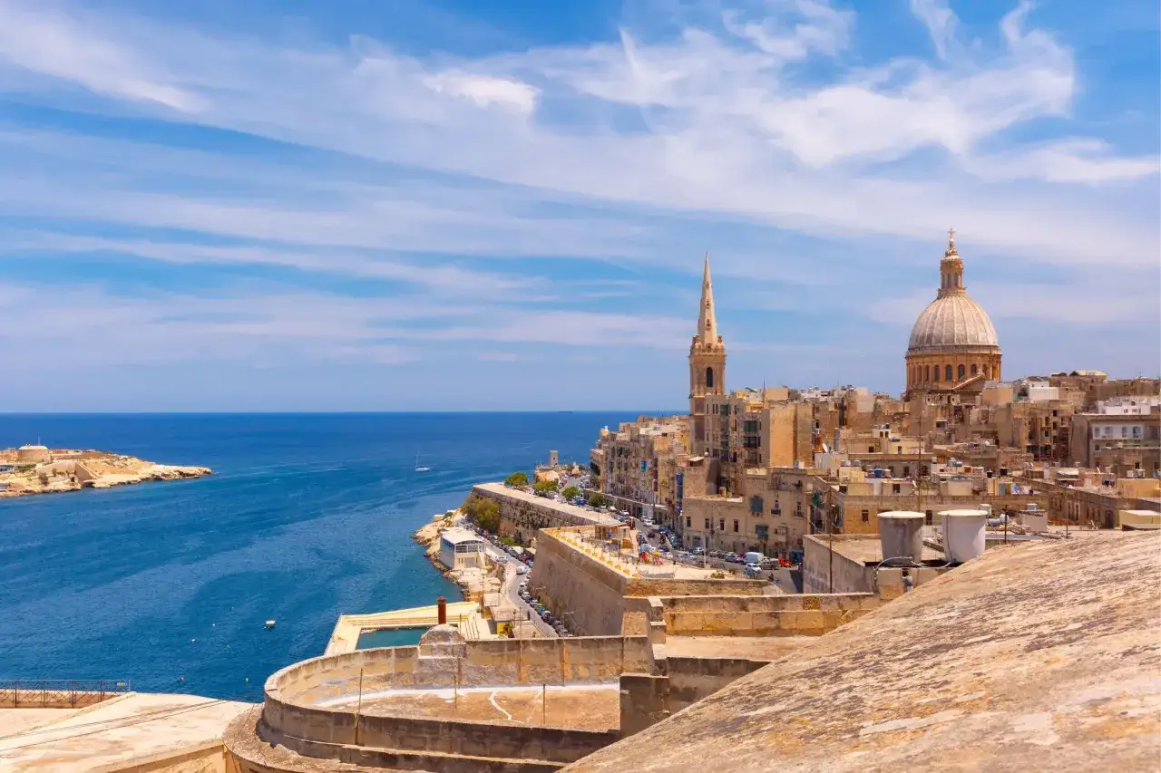 Widok na Vallettę, z kopułą i wieżą kościelną. Piękne morze i niebo. Malta ceny wakacji zachęcają do podróży.
