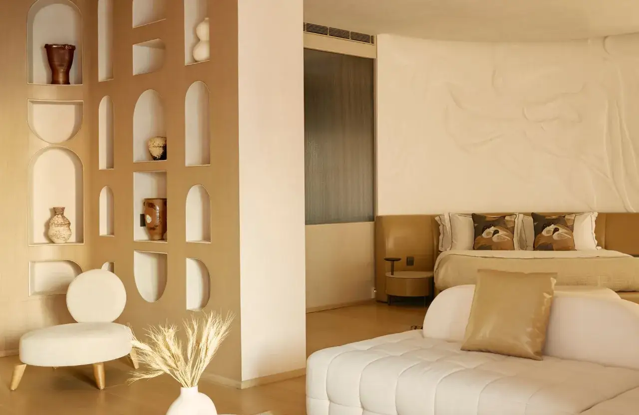 Un coin salon cosy avec une étagère murale décorée et un lit invitant, comme pour séparer une petite chambre en deux espaces distincts.