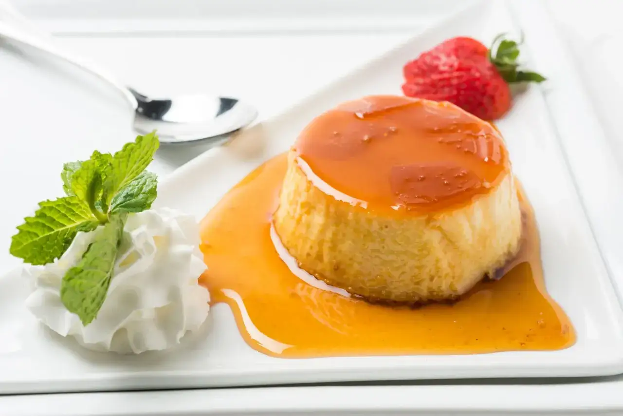 Un d&eacute;licieux g&acirc;teau de semoule napp&eacute; de caramel, garni de cr&egrave;me fouett&eacute;e, de menthe et d'une fraise.