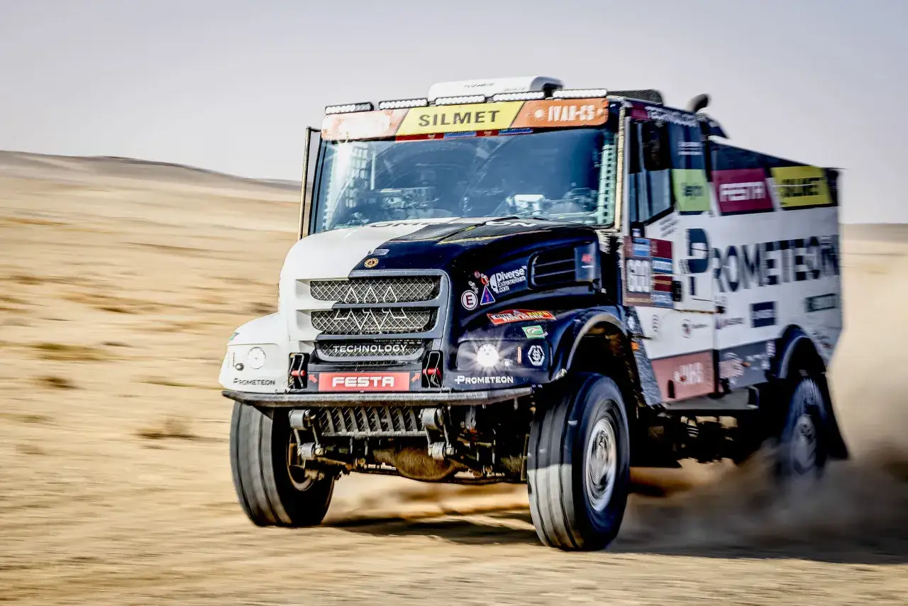 Un camion de course du Dakar, symbole de la puissance, fonce dans le d&eacute;sert, soulevant un nuage de poussi&egrave;re.