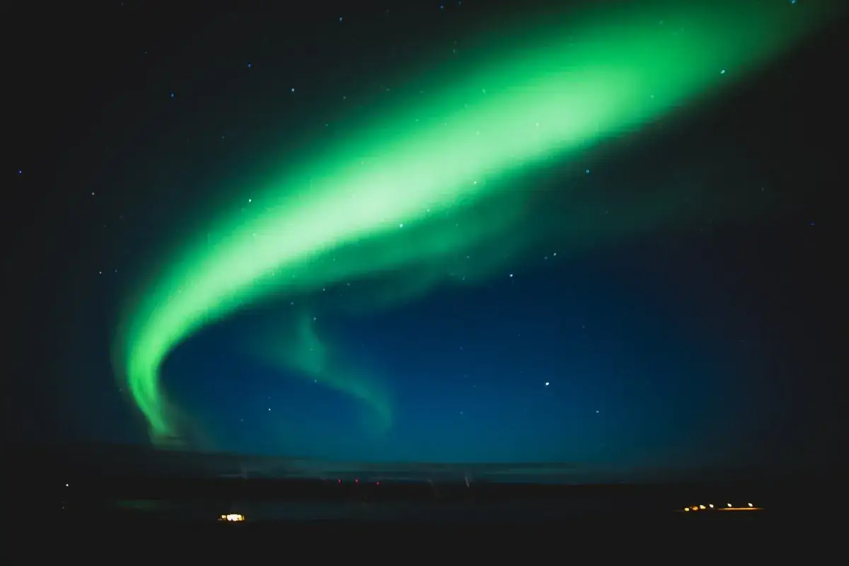 Zielona zorza polarna tańczy na nocnym niebie nad Islandią, tworząc magiczny spektakl.