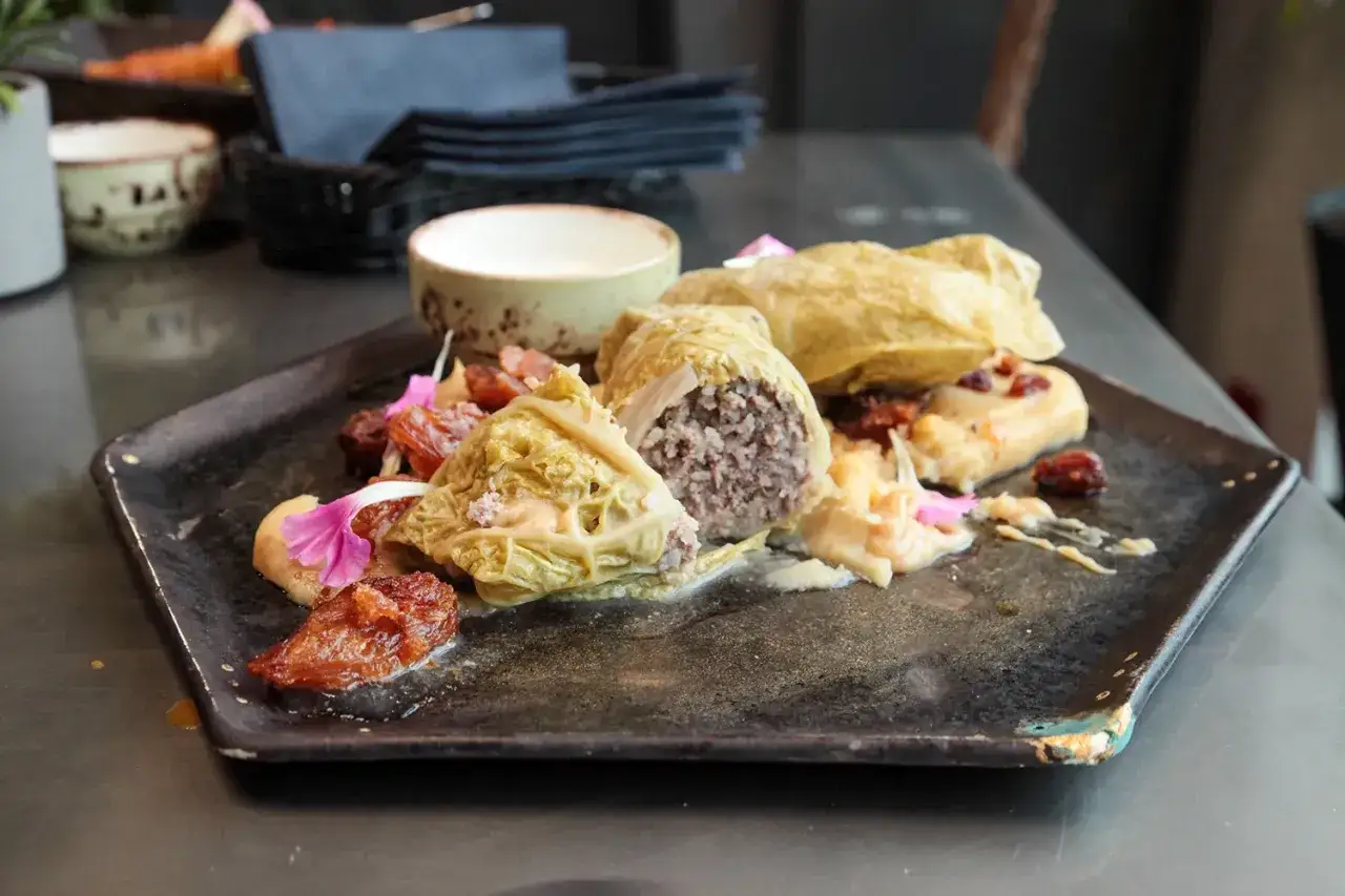 Golabki z kapusty z farszem mięsnym, podane z suszonymi pomidorami i kwiatami. Danie z menu Oria Magic House.