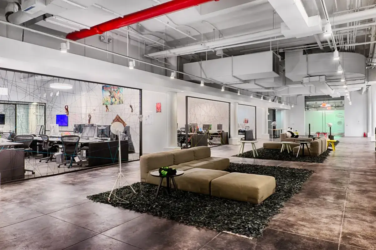 Modern office space at Spotify Studios NYC, featuring open workstations, lounge areas with plush seating, and artistic decor.