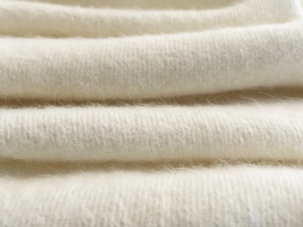 Miękkie, kremowe fałdy materiału angora, delikatne i puszyste, zapraszają do otulenia.