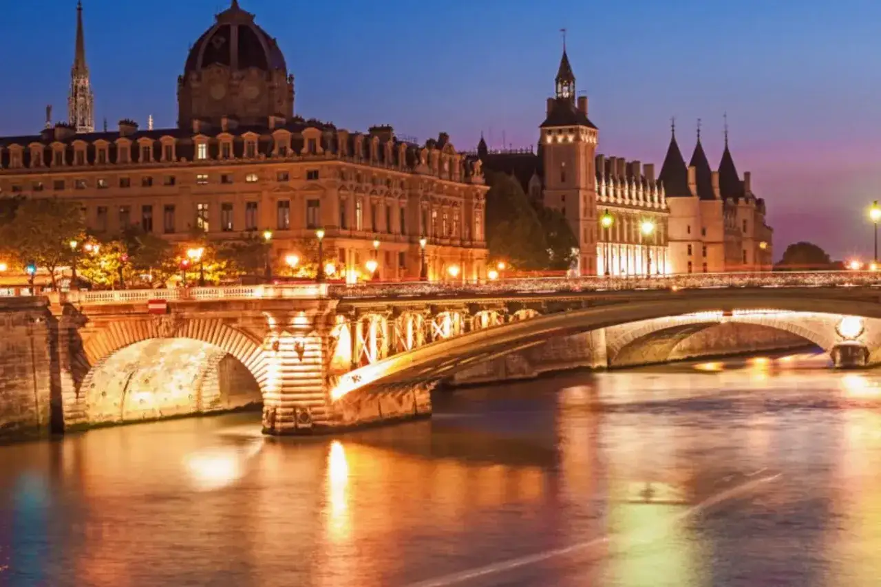 Pont Neuf illuminé, un incontournable pour un circuit touristique Paris à pied. La Seine reflète les lumières de la ville.