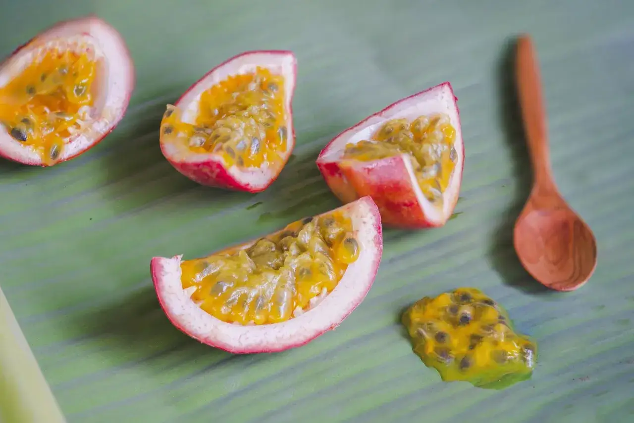 Fruits de la passion coupés en deux sur une feuille verte, avec une cuillère en bois. Saviez-vous quel est le fruit le plus riche en magnésium ?