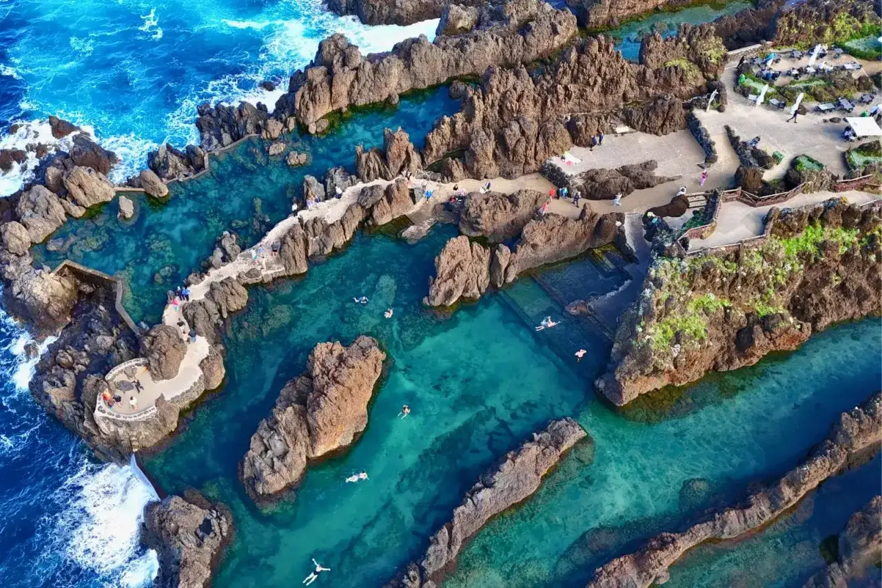 Naturschwimmbecken auf Madeira, ein Highlight der Insel. T&uuml;rkises Wasser umsp&uuml;lt vulkanische Felsen, Menschen schwimmen und entspannen.
