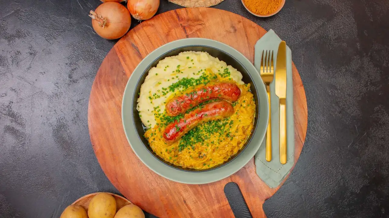 Herzhafte Bratwurst im Backofen mit Kartoffelpüree und Sauerkraut, garniert mit Schnittlauch. Ein Klassiker, der immer schmeckt.