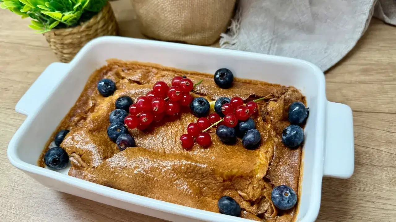Puszysty omlet z piekarnika, udekorowany świeżymi borówkami i czerwonymi porzeczkami, wygląda apetycznie.
