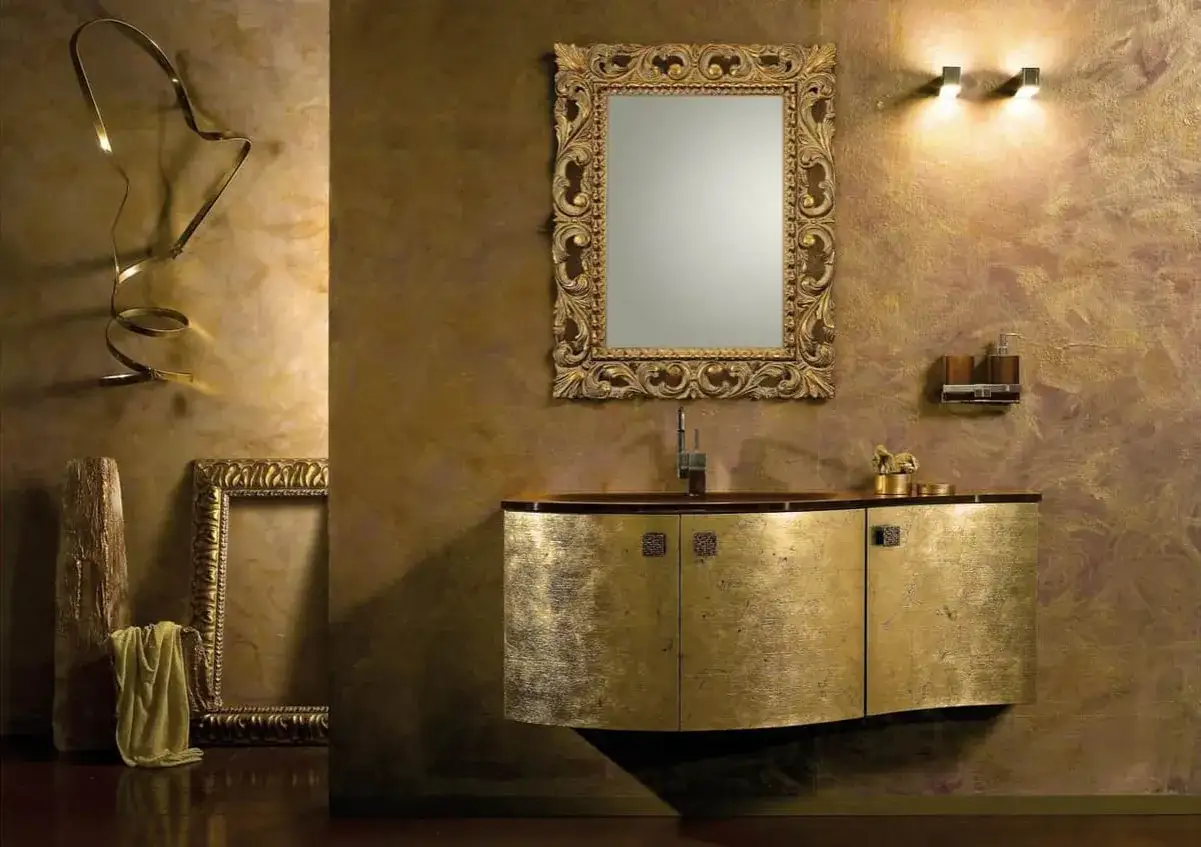 Salle de bain luxueuse avec un meuble-lavabo et un miroir ornés, le tout baigné d'une lumière dorée.