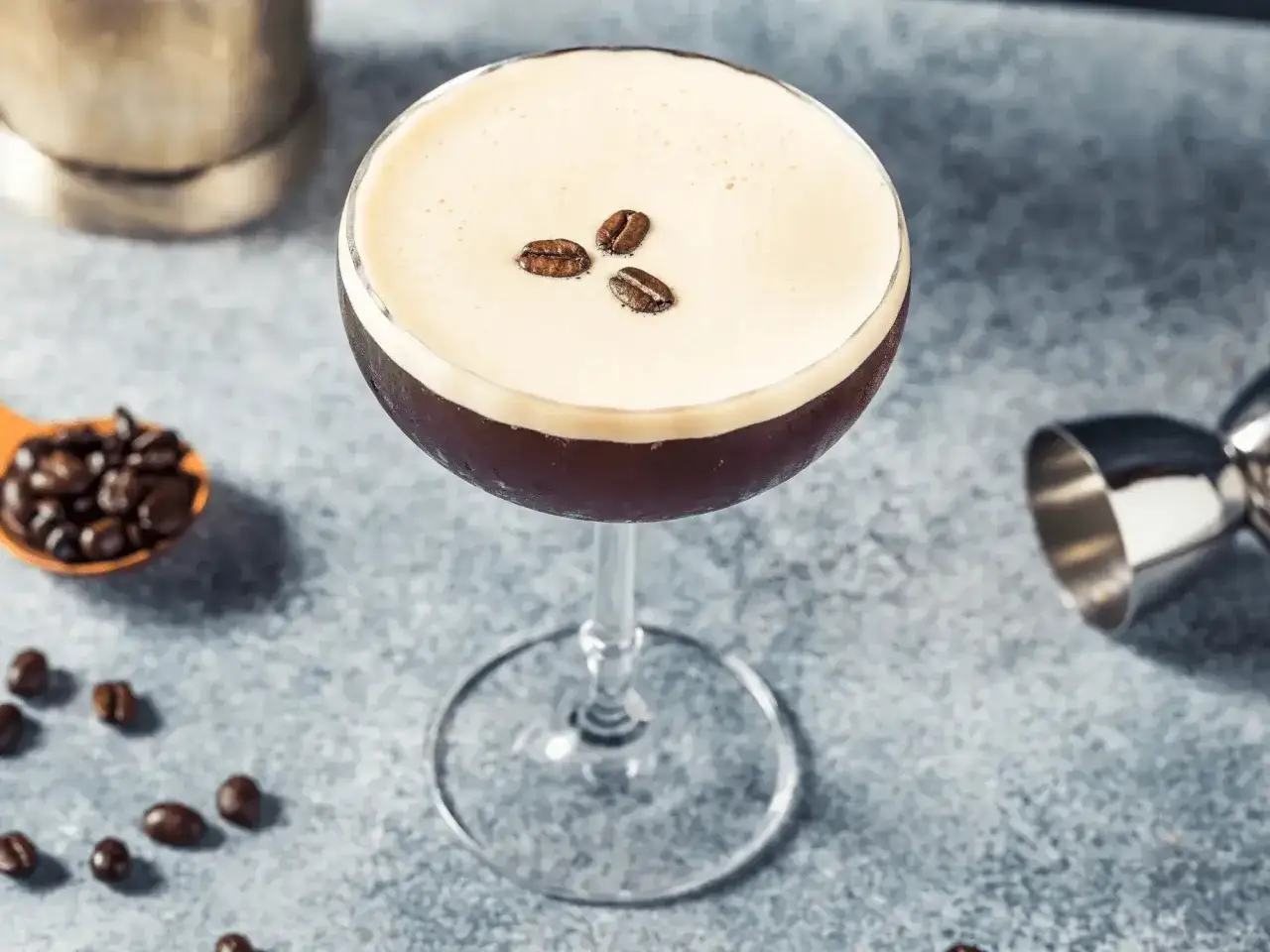 Elegancki drink z espresso, ozdobiony trzema ziarnami kawy, na eleganckim tle.