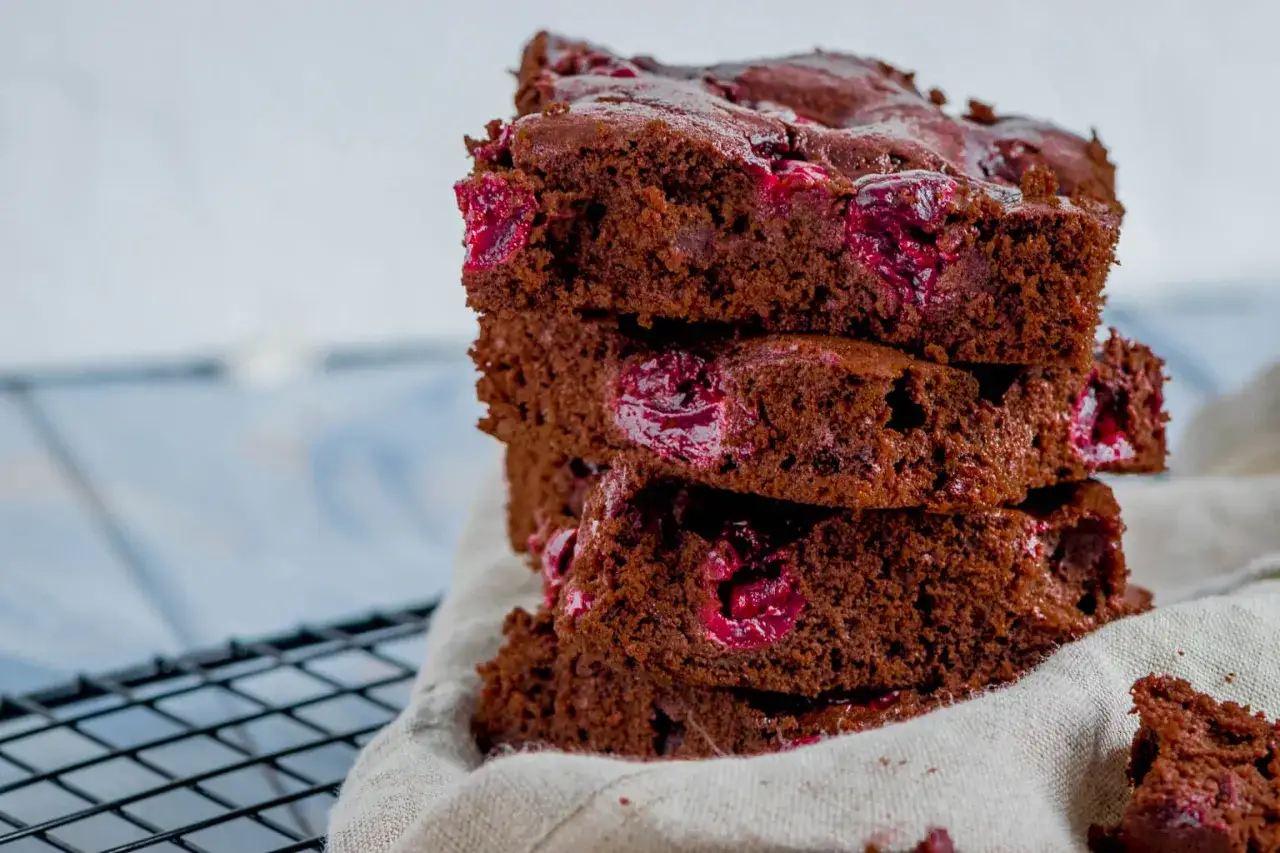 Ein Stapel saftiger St&uuml;cke vom Schoko Kirsch Kuchen Blech, mit saftigen Kirschen durchzogen.