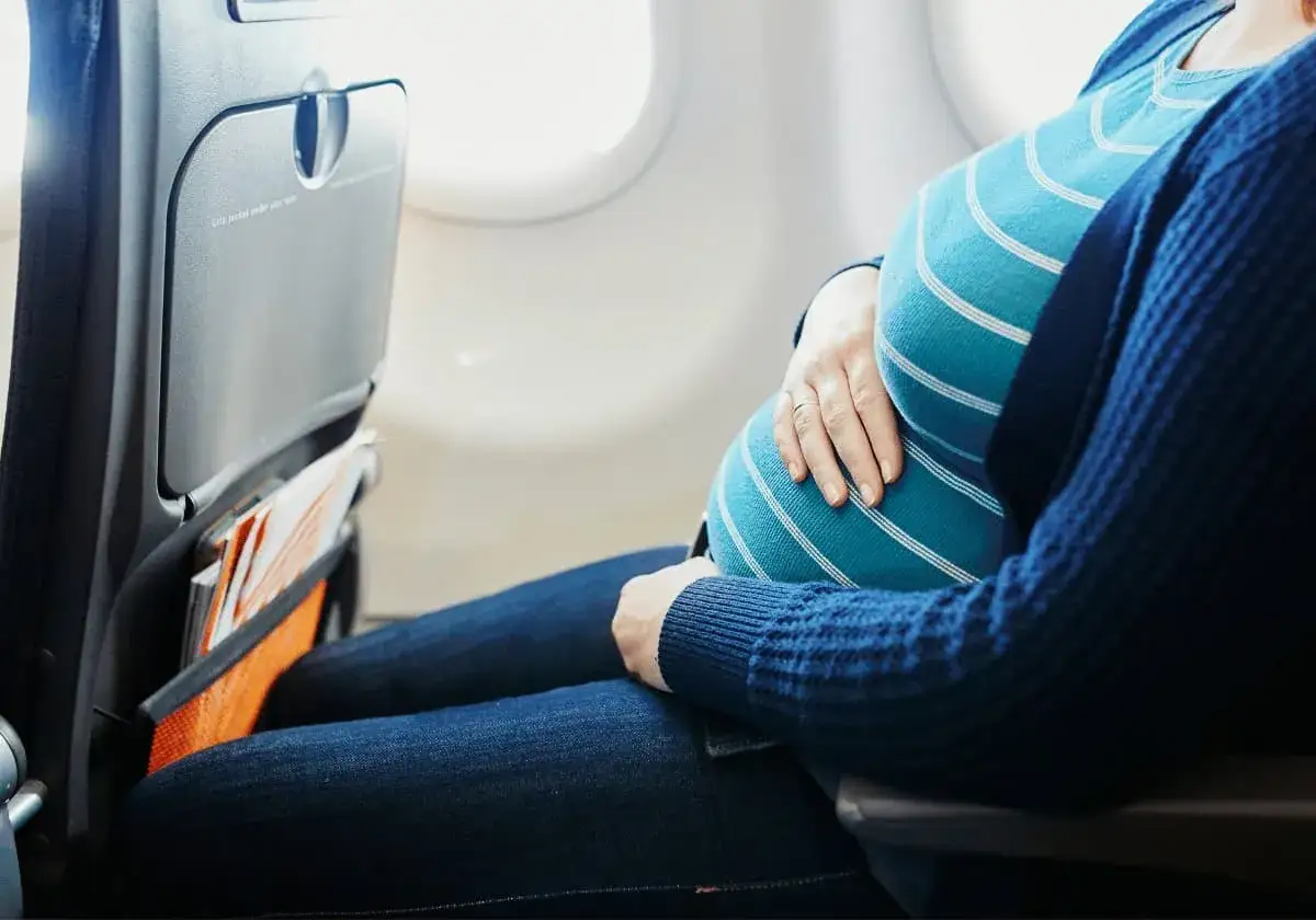 Gravid kvinna sitter vid flygplansfönstret, redo att flyga.