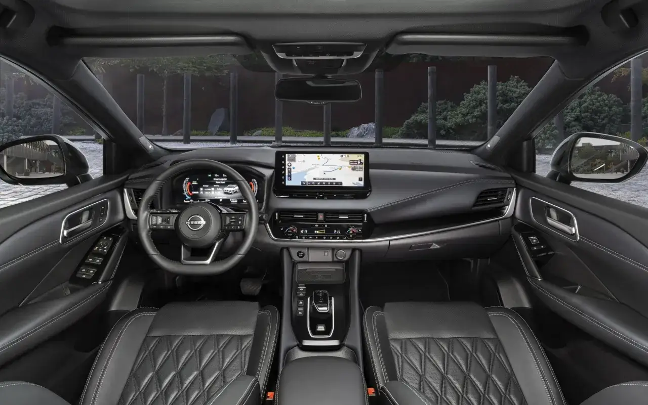Wnętrze nowego Nissan Qashqai 2025: cyfrowe zegary, duży ekran multimediów z nawigacją i komfortowe, pikowane fotele.
