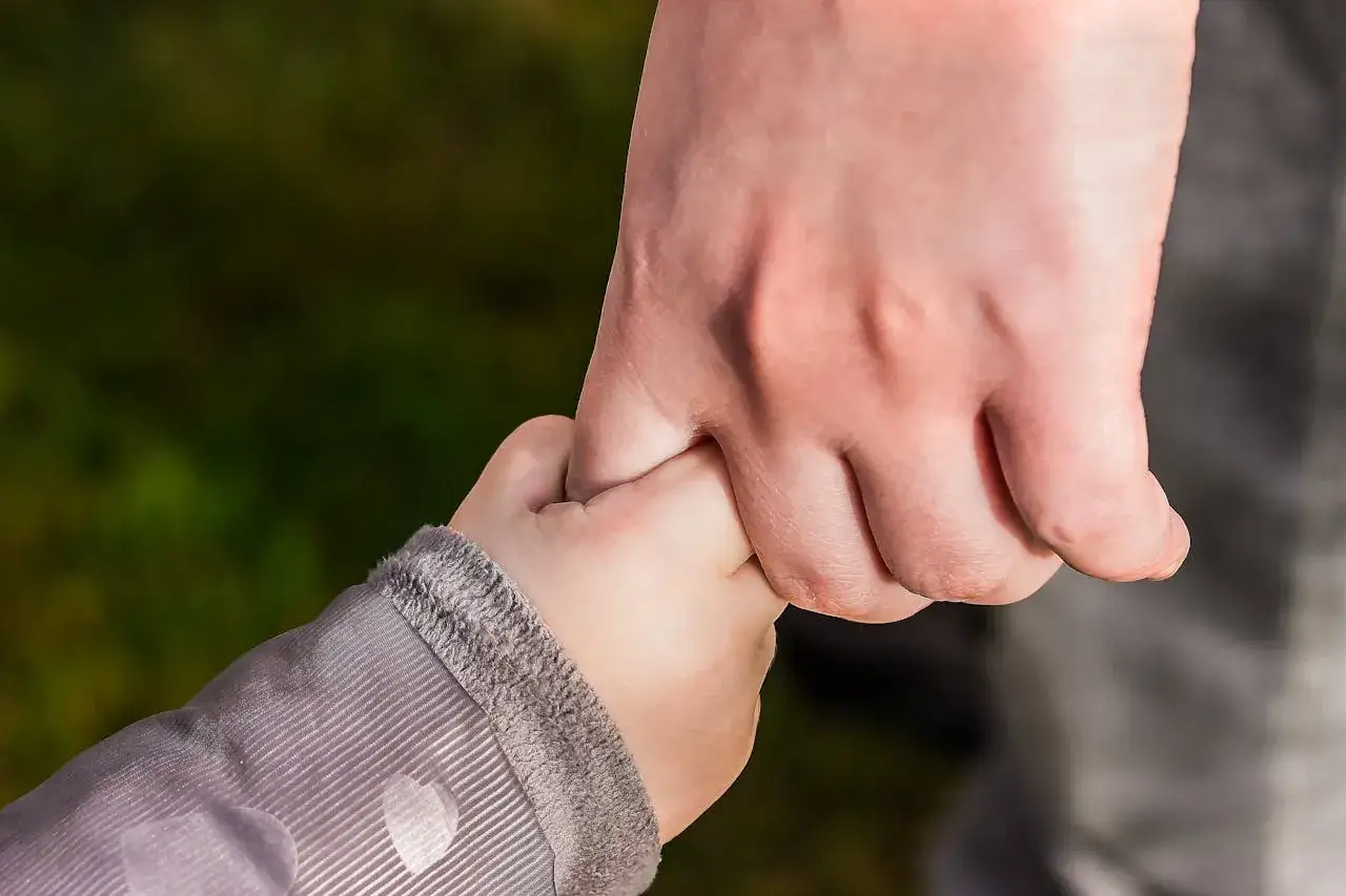 Dłoń dziecka trzymająca dłoń dorosłego. Symbol wsparcia i troski, ale też potencjalnego ograniczenia władzy rodzicielskiej.