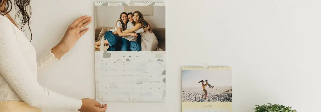 Un calendario personalizado con fotos de amigos y familia. Un mes muestra a tres amigas abraz&aacute;ndose, otro a una madre jugando con su hijo en la playa.