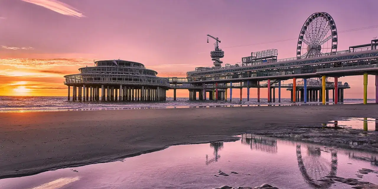 Sonnenuntergang am Pier in Den Haag. Ein Riesenrad und bunte Pfeiler versprechen tolle Den Haag Unternehmungen.